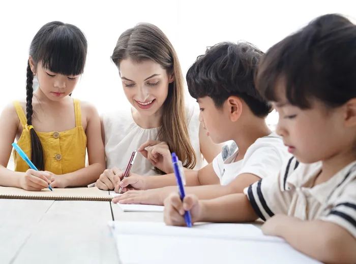 ノートに書いて英語を学ぶ児童たちと外国人教師